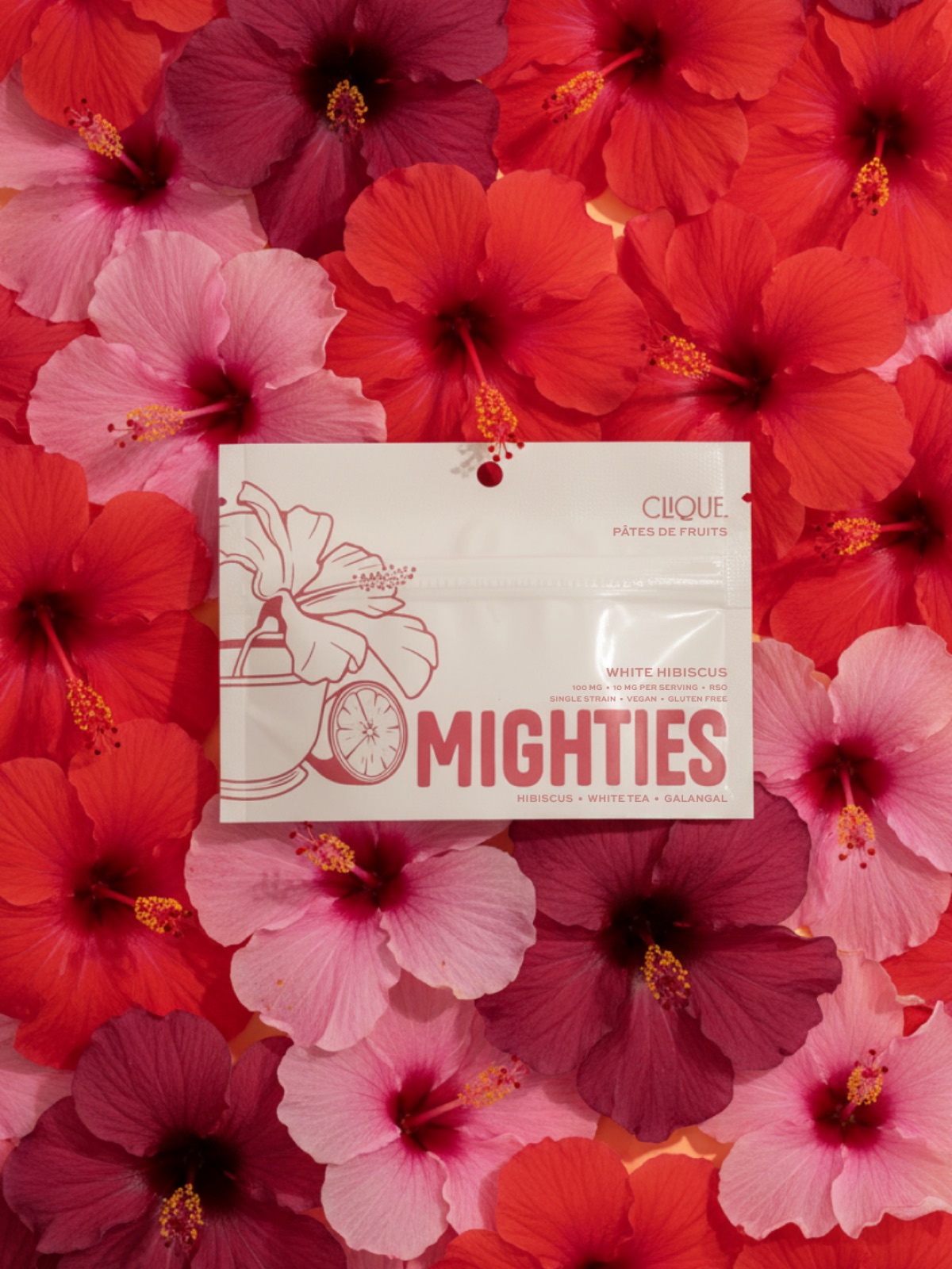 Clique Mighties White Hibiscus package resting on a bed of red hibiscus flowers