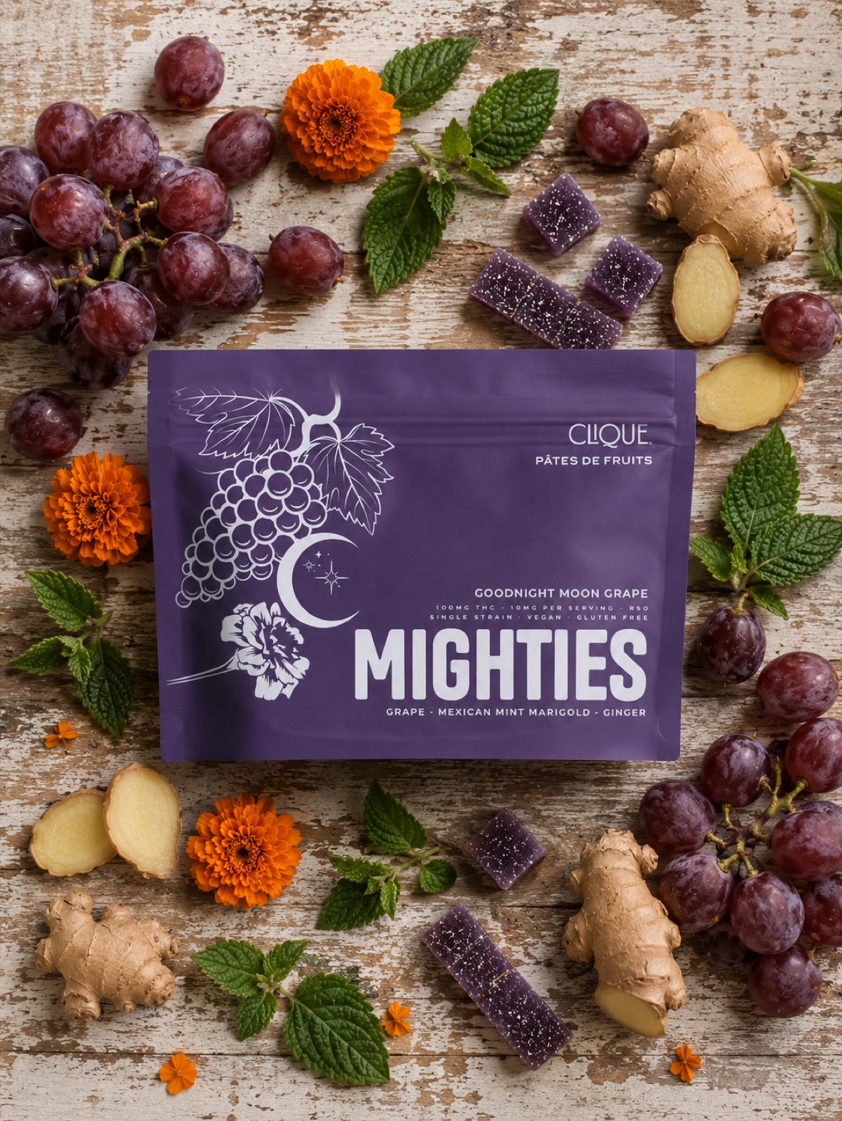 Clique Mighties package surrounded by grapes, marigolds, ginger, and mint